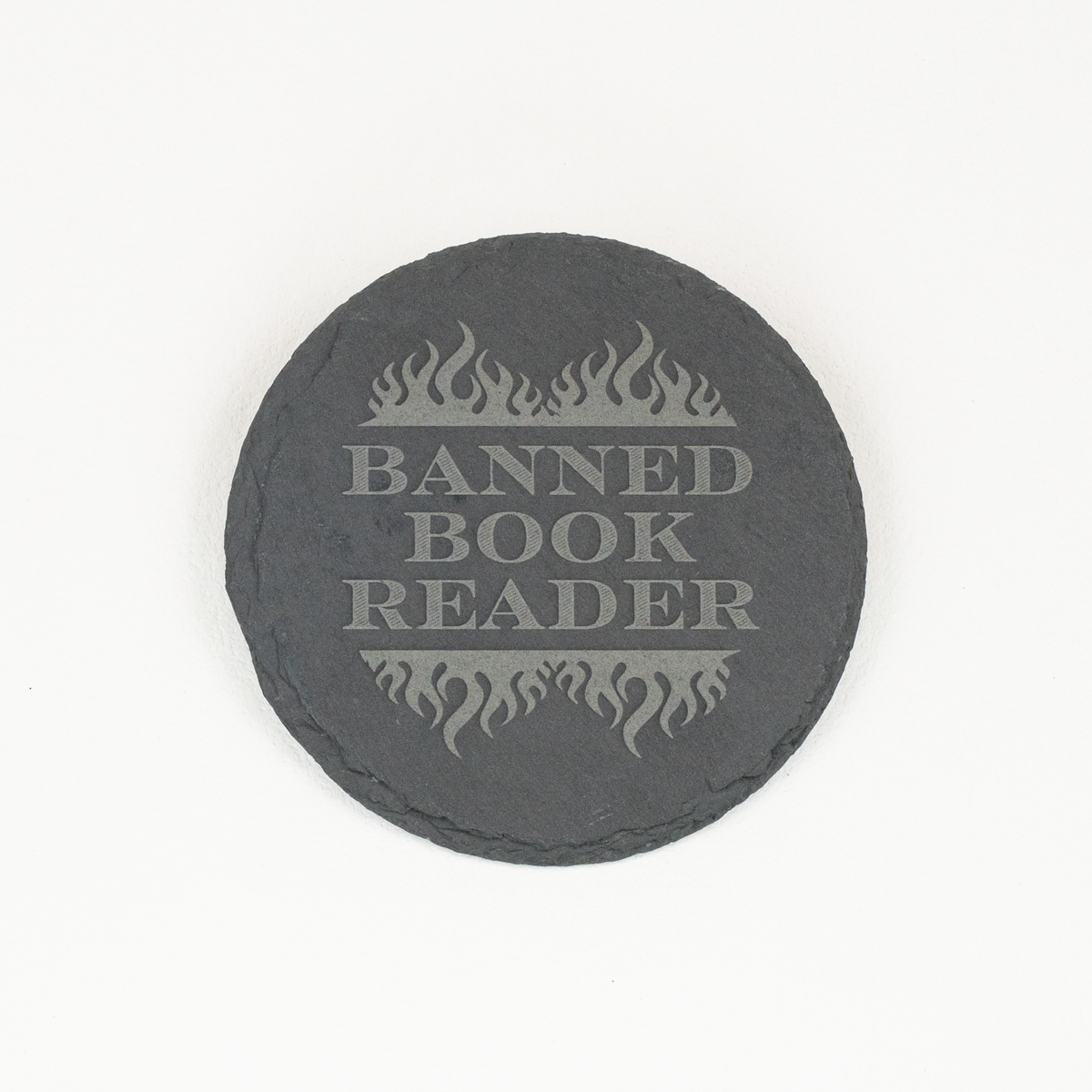 A round dark gray slate coaster with a light gray engraved design featuring flames and the text 'BANNED BOOK READER', shown on a plain white background.