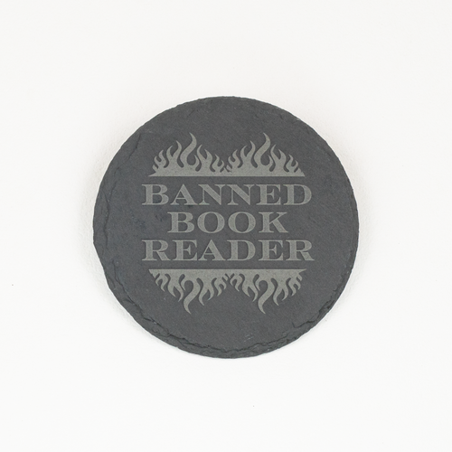 A round dark gray slate coaster with a light gray engraved design featuring flames and the text 'BANNED BOOK READER', shown on a plain white background.