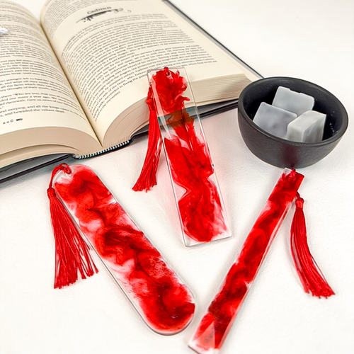 Three various sized resin bookmarks with blood-like swirls and glitter, with red tassels.