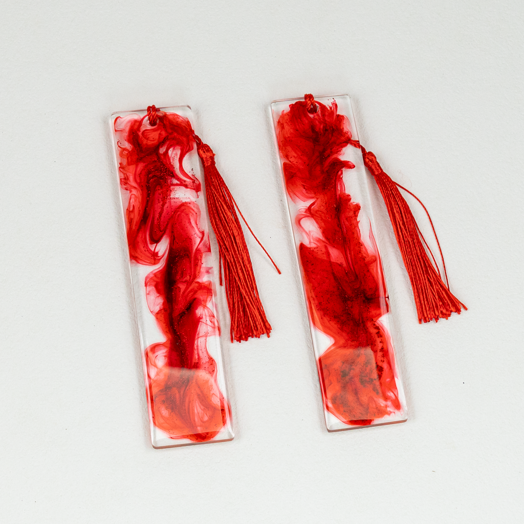 Two rectangle clear and red resin bookmarks with blood-like swirls and glitter, including red tassels.