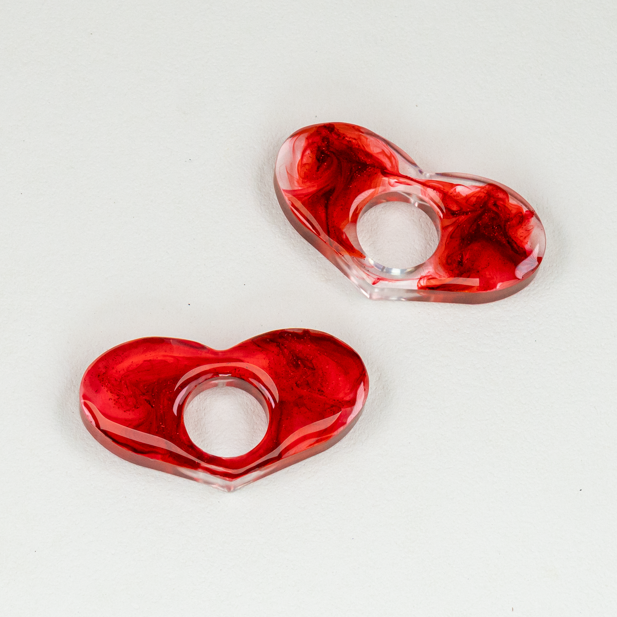 Two clear and red blood-like swirled heart-shaped page spreaders on white background.
