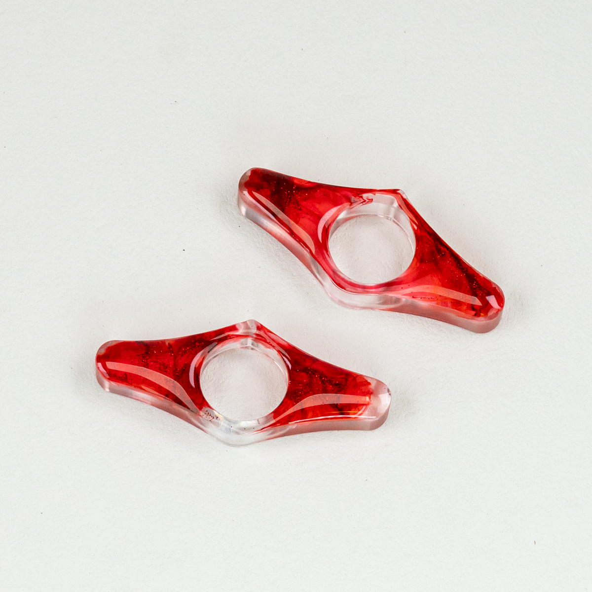 Two wing-shaped blood-swirled resin page spreaders on white background.