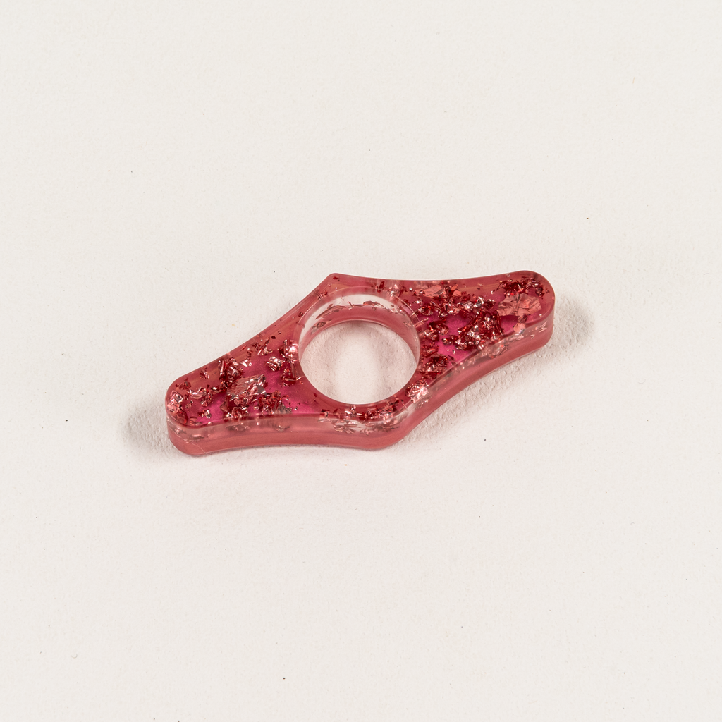 Wing-Shaped pink resin page spreader with glittery pink foil over opaque pink backing.