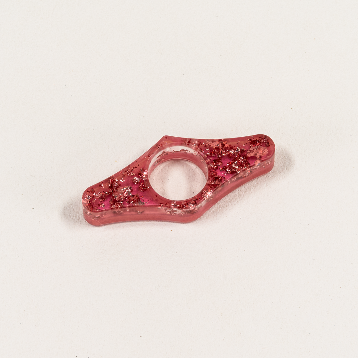 Wing-Shaped pink resin page spreader with glittery pink foil over opaque pink backing.