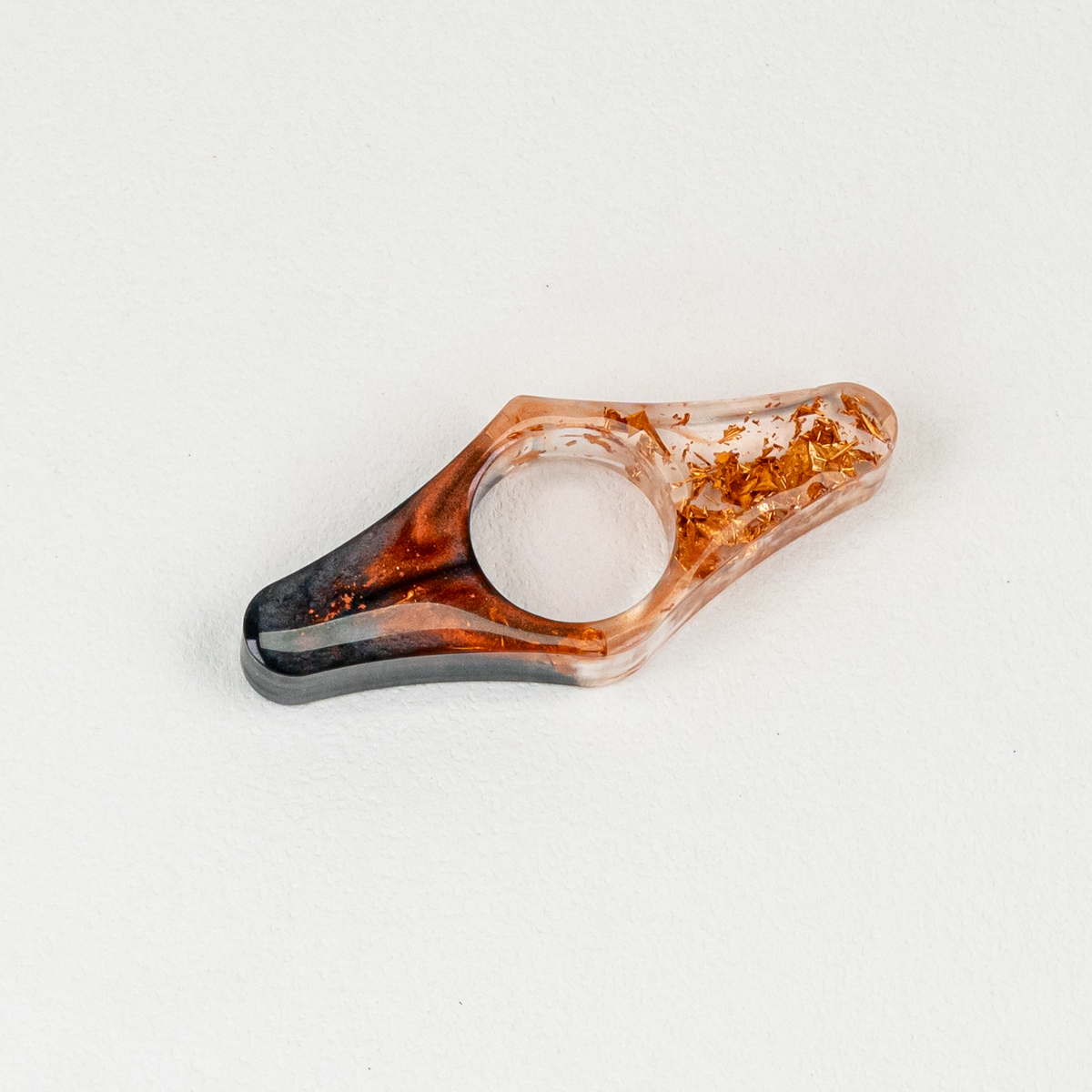 A wing-shaped resin thumb page holder in onyx, burnt orange, and copper resin on white background.