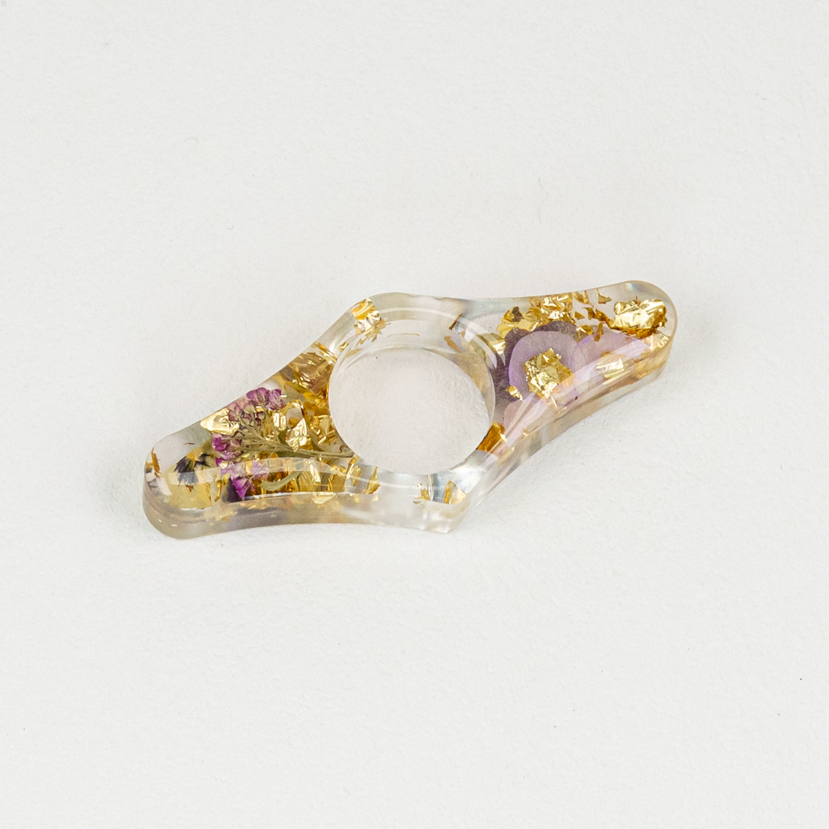 Wing shaped clear resin thumb page holder in gold flakes with flowers.