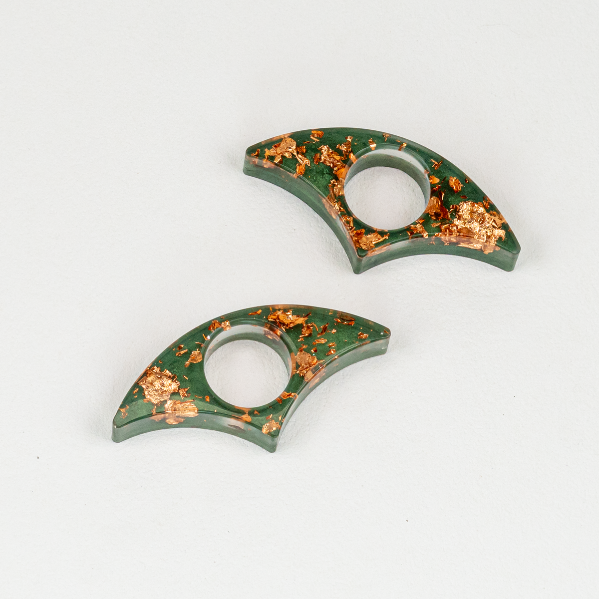 Two fan-shaped resin page holders with copper flakes over top hunter green resin on white background.