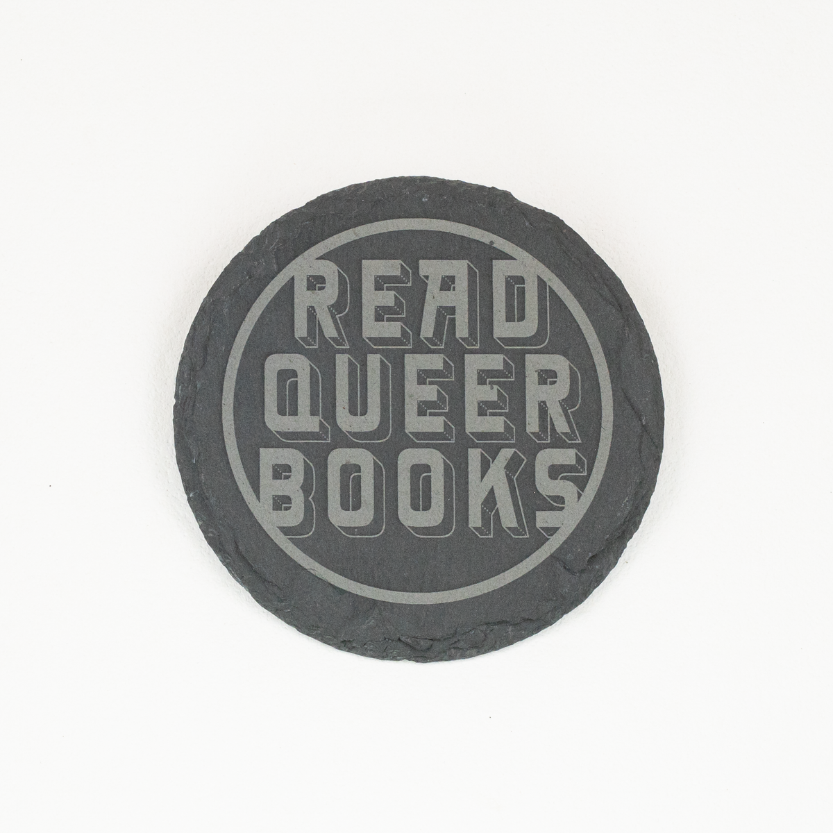 Single round slate coaster with 'Read Queer Books' engraved in stylized font within a circle.