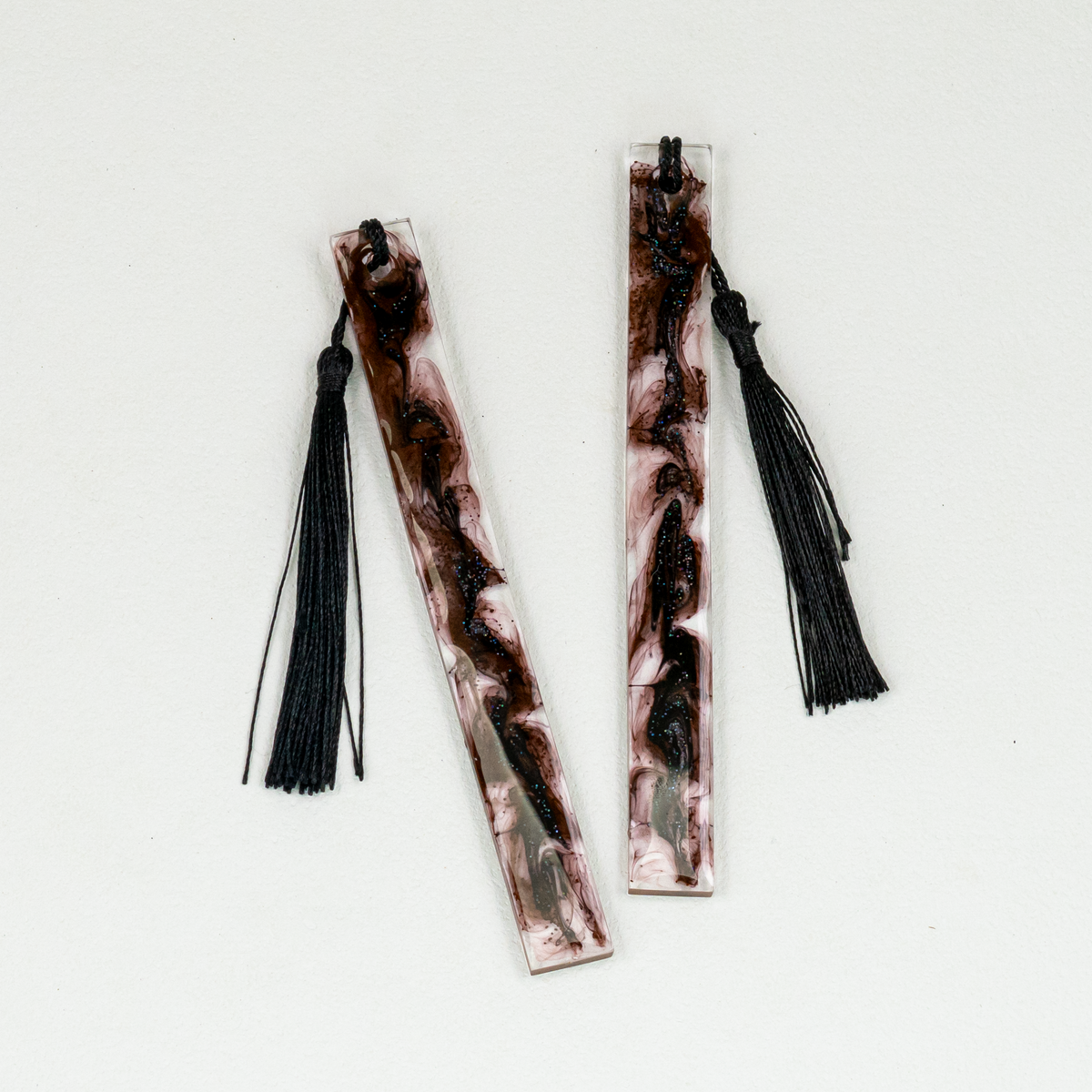Two slim rectangle bookmarks with black swirls and black tassels.
