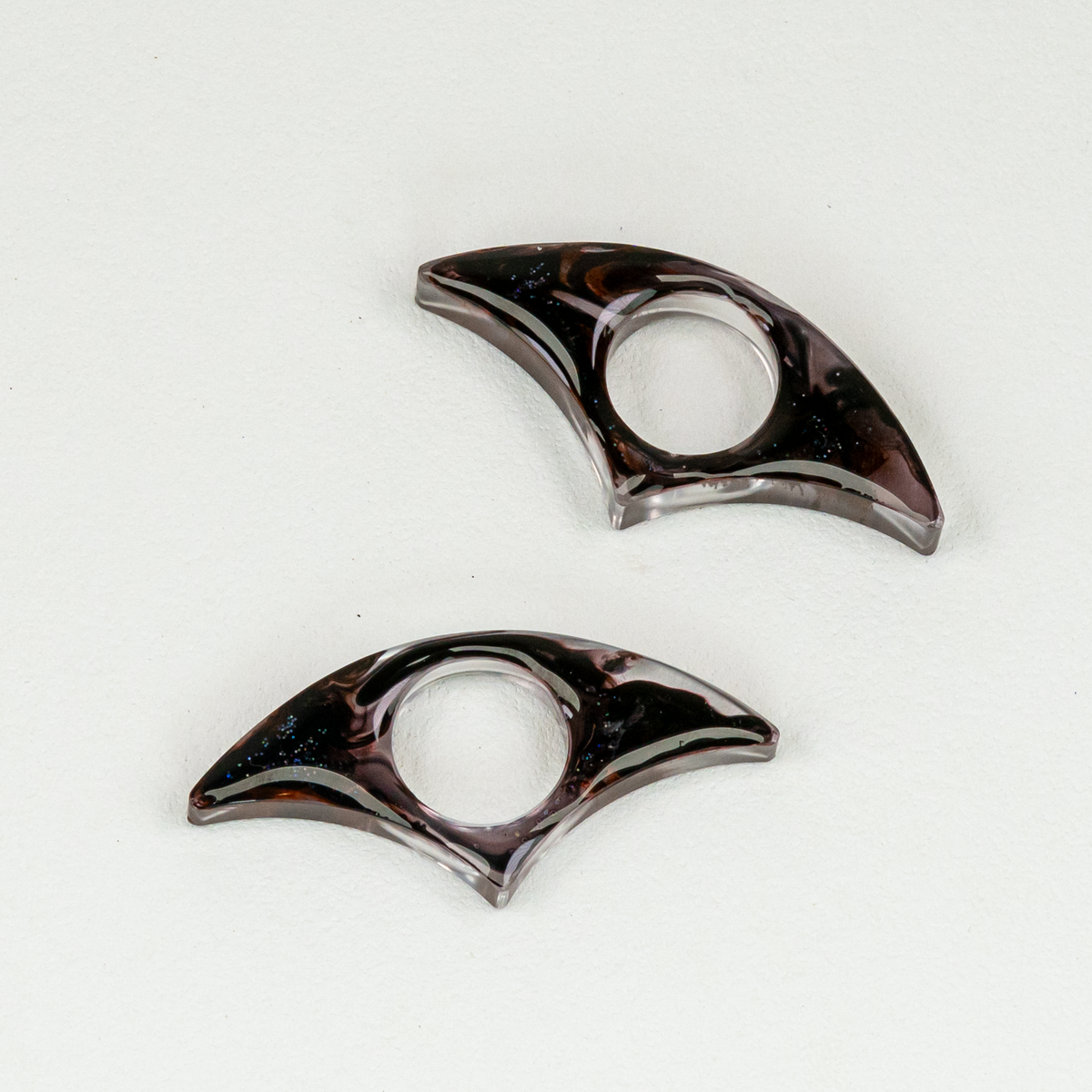 Two fan-shaped resin bookmarks with swirls of black and glitter.
