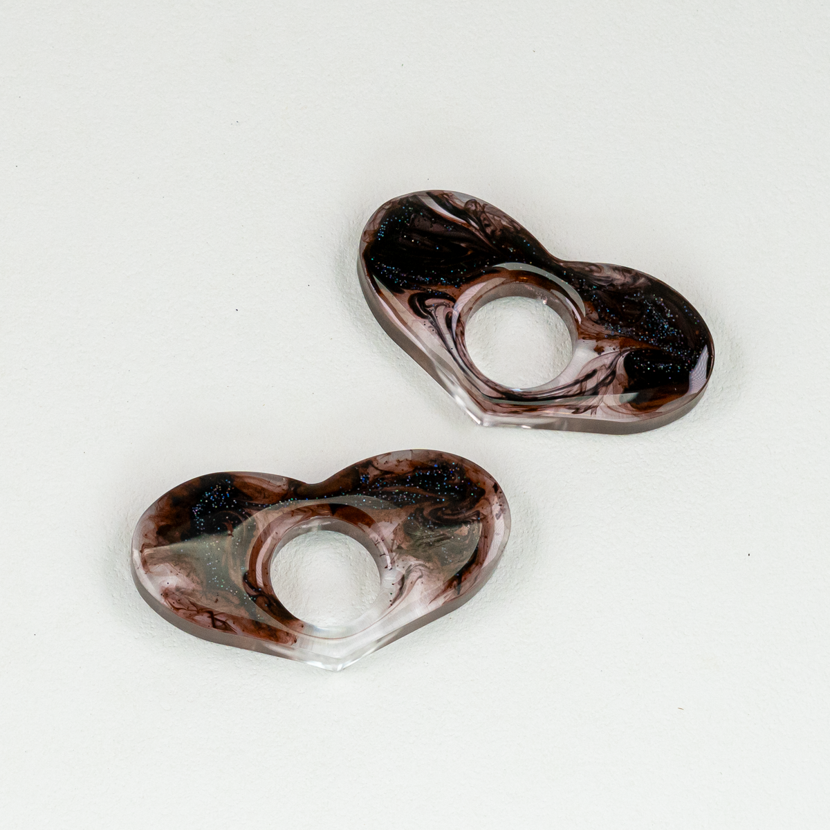 Two heart-shaped resin bookmarks with swirls of black and glitter.
