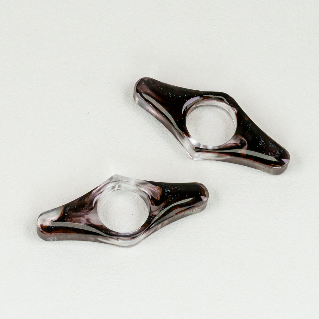 Two wing-shaped resin bookmarks with swirls of black and glitter.